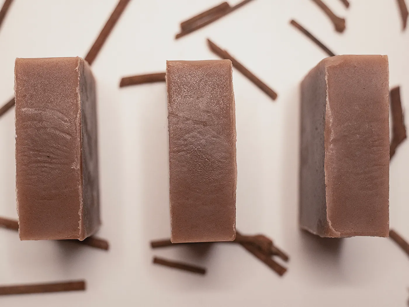 Three bars of Ruby Root soap from above, scattered madder root around them